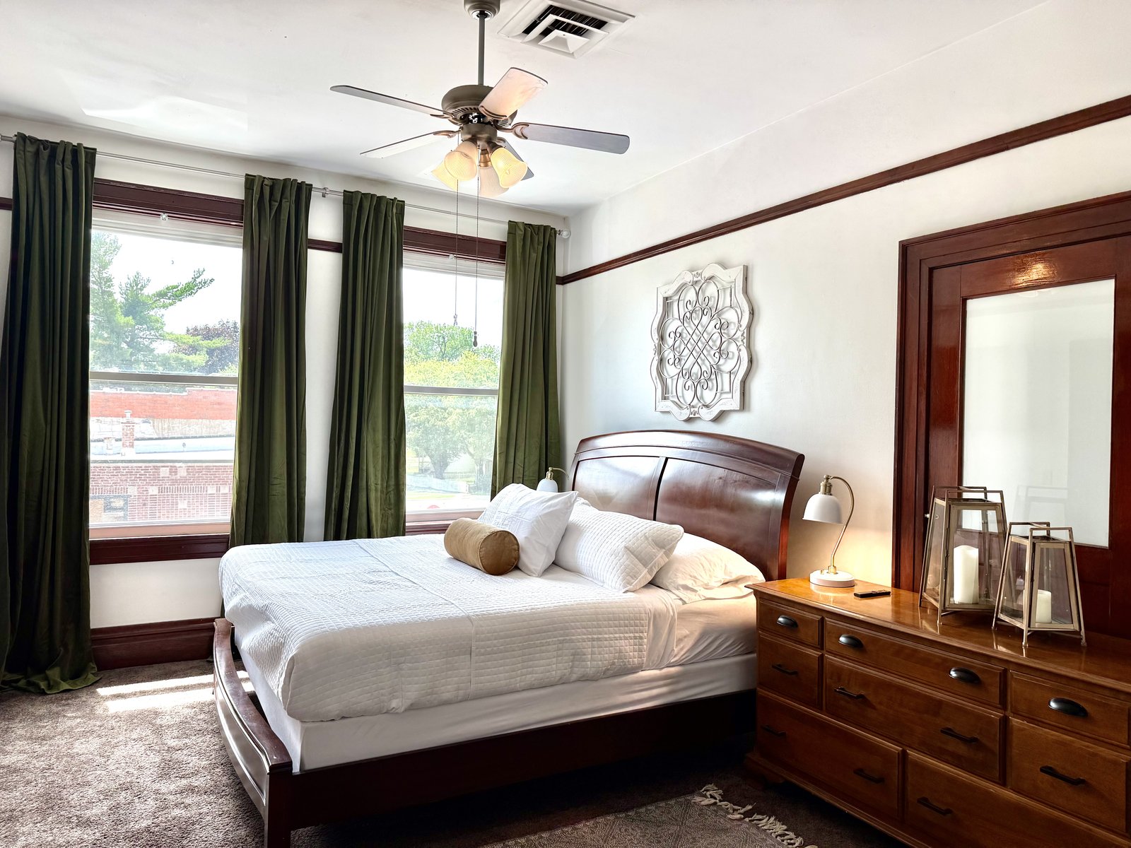 Master bedroom — wood sleigh bed, green curtains, ceiling fan