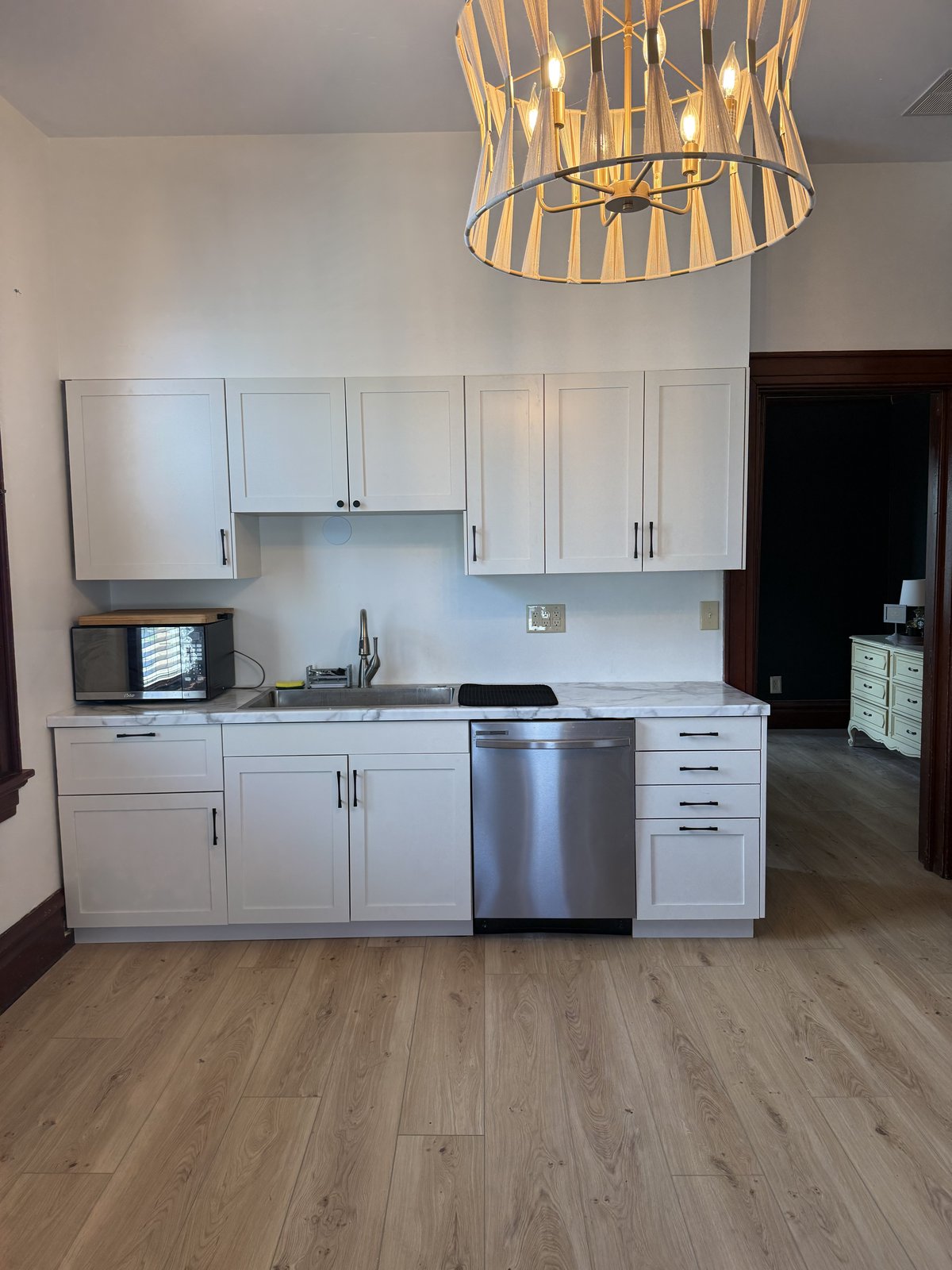 Kitchen — white shaker cabinets, marble countertops, woven chandelier
