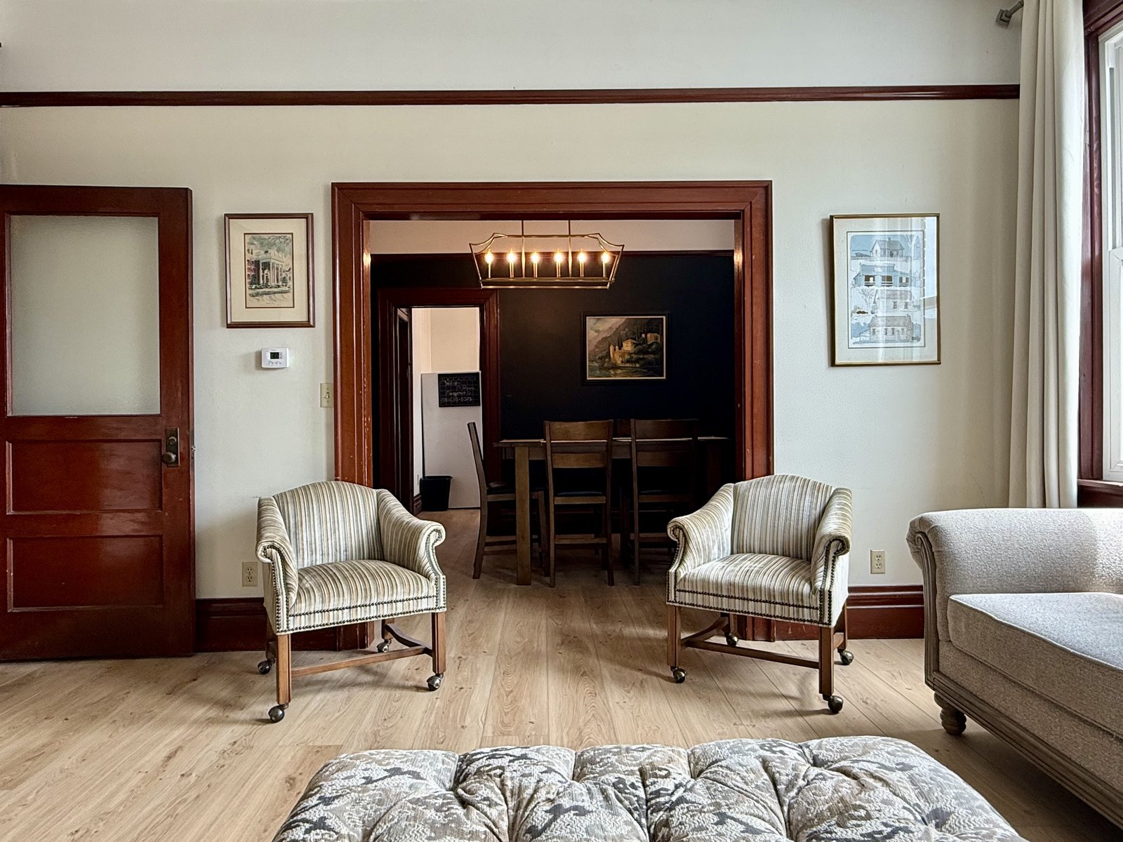Living room — striped armchairs, ottoman, and view into dining room